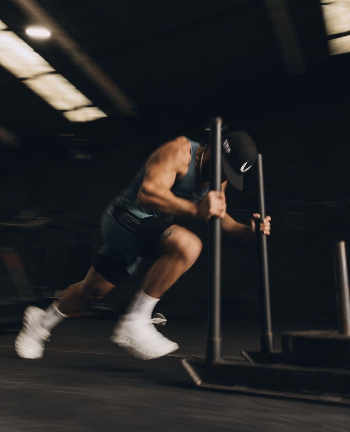 Athlète poussant un sled dans une salle sombre